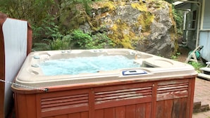 Ein Whirlpool in einer Außenanlage mit Felsen und viel Grün.