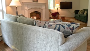 Ein Wohnzimmer mit Kamin, Fernseher und einem grünen Sofa.