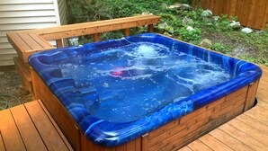 A hot tub with a wooden deck and a wooden bench.