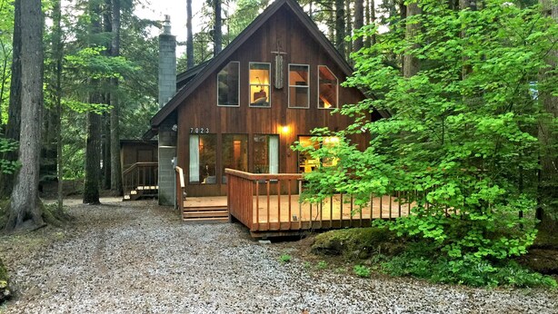 A cabin with a wooden exterior, multiple windows, a deck, and a gravel driveway surrounded by trees. - Snowline Cabin 35 - A Pet-friendly Country Cabin, Now has air Conditioning! (Deming)