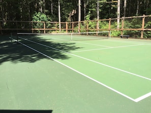 A tennis court with a wooden fence and trees in the background. - Snowater Condo #38 - A Great Mountain Retreat! (Deming)