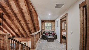 A wooden staircase leading to a loft bedroom with a view of the outdoors. - Glacier Springs Cabin #39 - New Modern-rustic Cabin With Air Conditioning! (Deming)