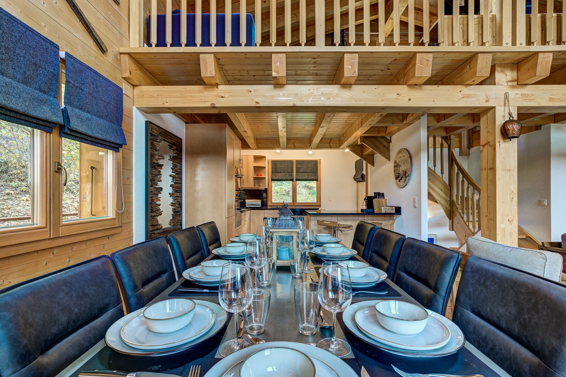 Un espace repas avec une longue table dressée pour six personnes, entourée de banquettes en cuir foncé.