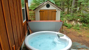 A hot tub in a wooded backyard with a wooden deck and a small wooden structure. - Glacier Springs Cabin 2bedrooms, 2 Baths - hot tub & Pet Friendly! (Deming)