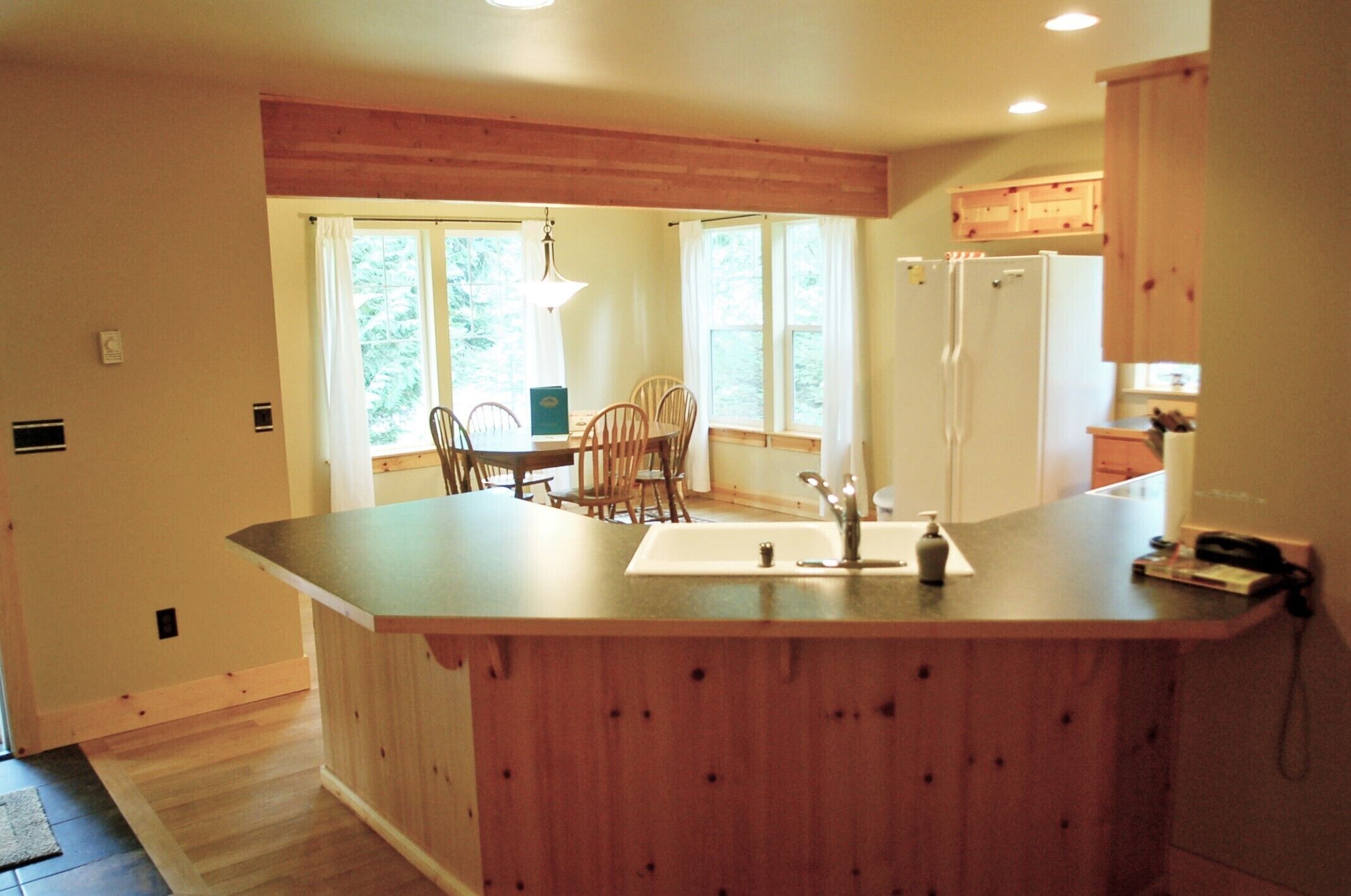 A kitchen with wooden cabinets, a central island with a sink, and a refrigerator.