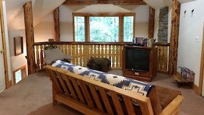 A cozy room with a wooden bench, a television, and a stone wall. - Snowline Cabin #25 A Country-style pet Friendly Cabin With hot tub and Wifi! (Deming)