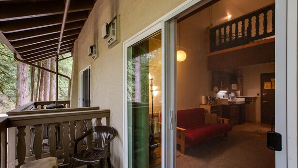 A cozy room with a wooden deck, a sliding glass door leading to a kitchen, and a red sofa. - Snowline Lodge - Condo 56 - Sleeps 4 - Close to Mt Baker Now has Wifi (Deming)