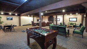 A room with a foosball table, green sofas, and a TV screen. - Snowline Lodge - Condo 56 - Sleeps 4 - Close to Mt Baker Now has Wifi (Deming)