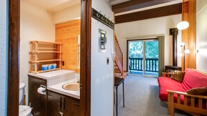 A compact room with a wooden floor, a red sofa, a wooden cabinet with a sink, and a staircase leading to a balcony. - Snowline Lodge - Condo 56 - Sleeps 4 - Close to Mt Baker Now has Wifi (Deming)