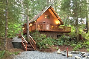 A cabin with a wooden exterior, a balcony, and a staircase leading to the entrance. - Snowline Cabin #98 A pet Friendly Cabin With a Wood Stove, hot tub and Wifi! (Deming)