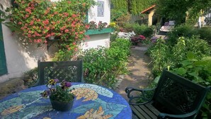 A garden with a mosaic table and chairs, surrounded by various plants and flowers. - Apartment Under Cedar (Sobotka)
