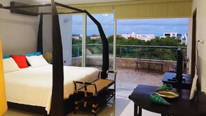 Ein Schlafzimmer mit Bett, Stuhl, Tisch und einem Balkon mit Aussicht.