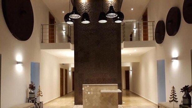 Eine geräumige Lobby mit einer zentralen Rezeption, hohen Decken und moderner Pendelleuchten.