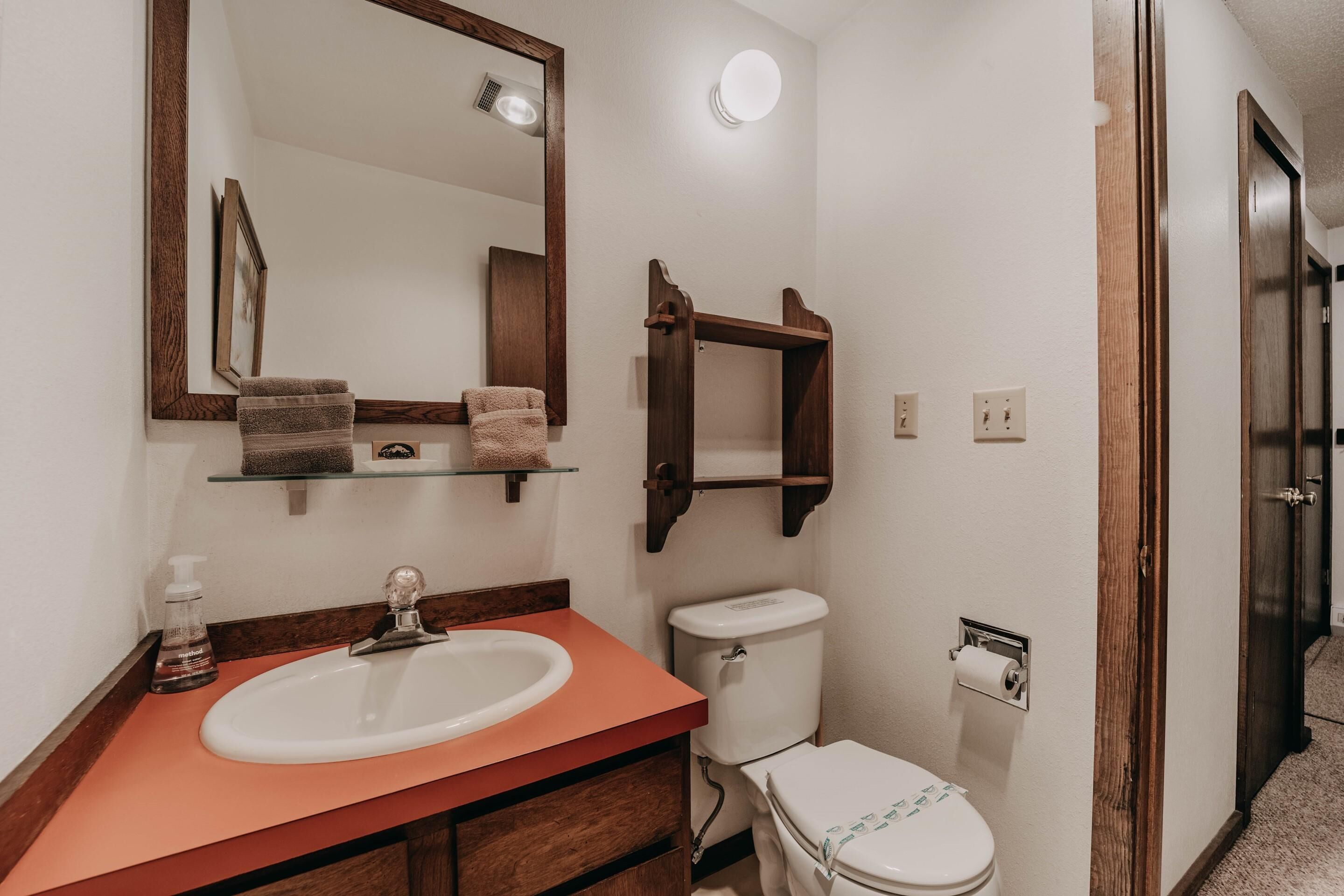 A bathroom with a sink, mirror, toilet, and towel rack.