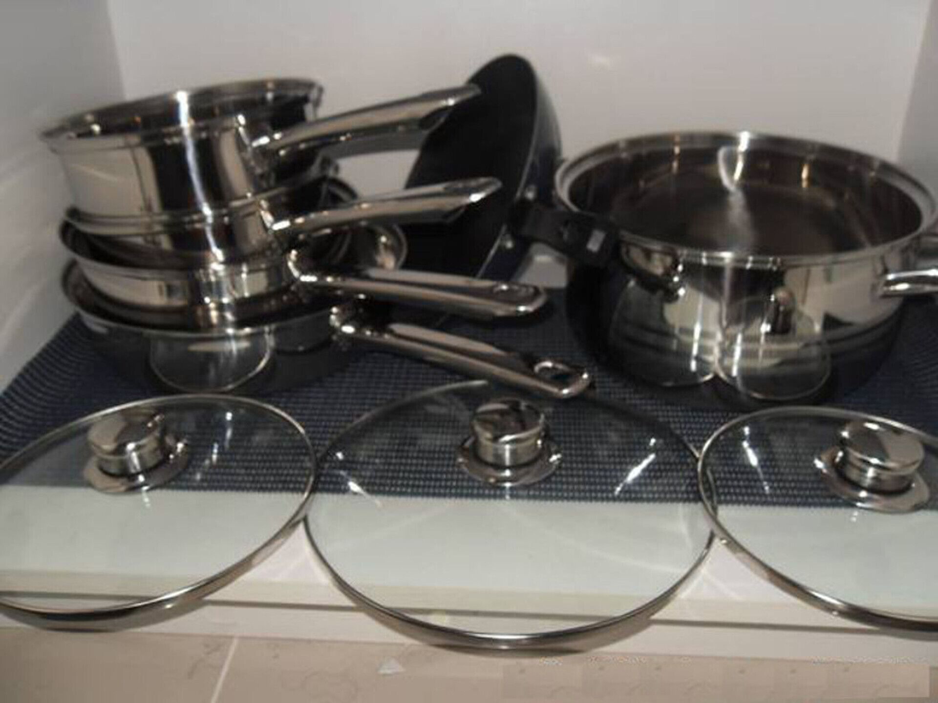 A kitchen with stainless steel cookware and lids.
