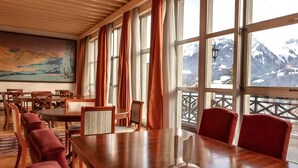 Une salle de conférence dotée d’une grande table et de chaises, de grandes fenêtres avec des rideaux et offrant une vue sur les montagnes.