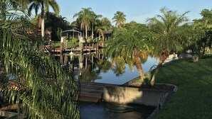 Um lago tranquilo com palmeiras, um cais de madeira e um gazebo.