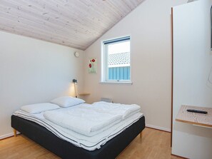 Une chambre à coucher avec un lit, une table de chevet, une lampe, une fenêtre et une porte.