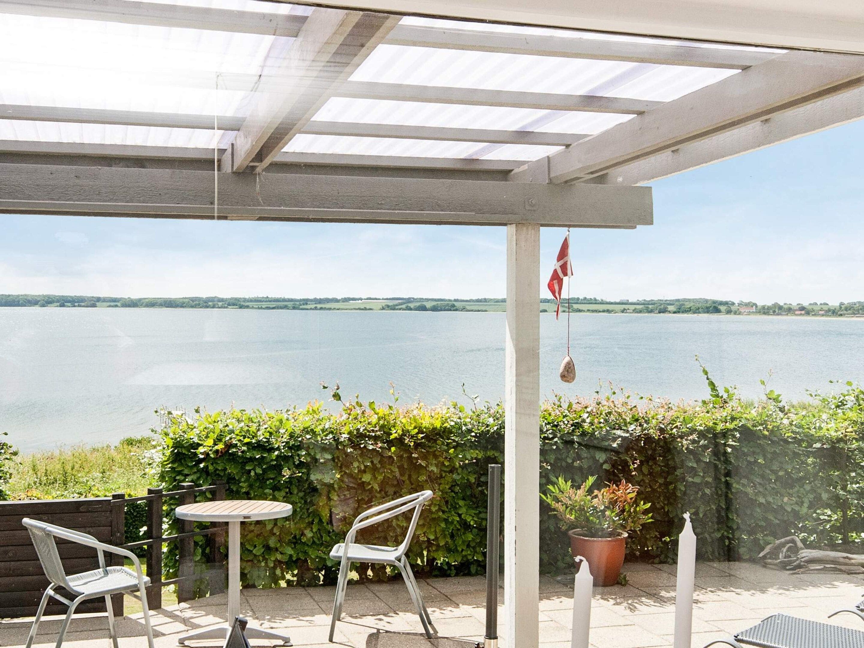 A covered outdoor seating area with a view of a lake.
