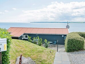 Et hus med rødt tegltag, en parabolantenne og udsigt til en sø.