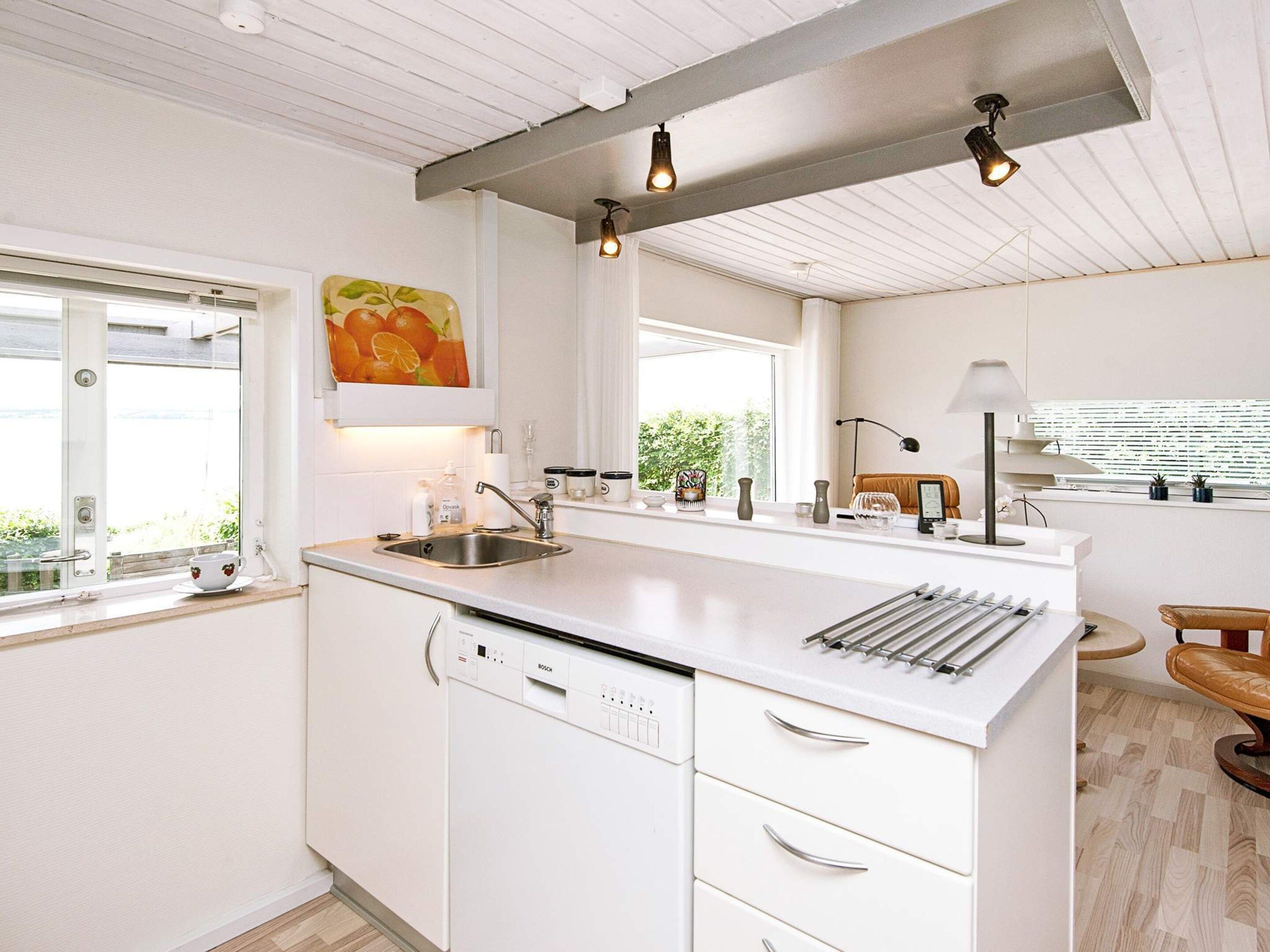 A modern kitchen with white cabinetry, a Bosch dishwasher, a sink, and a window with a view of greenery.