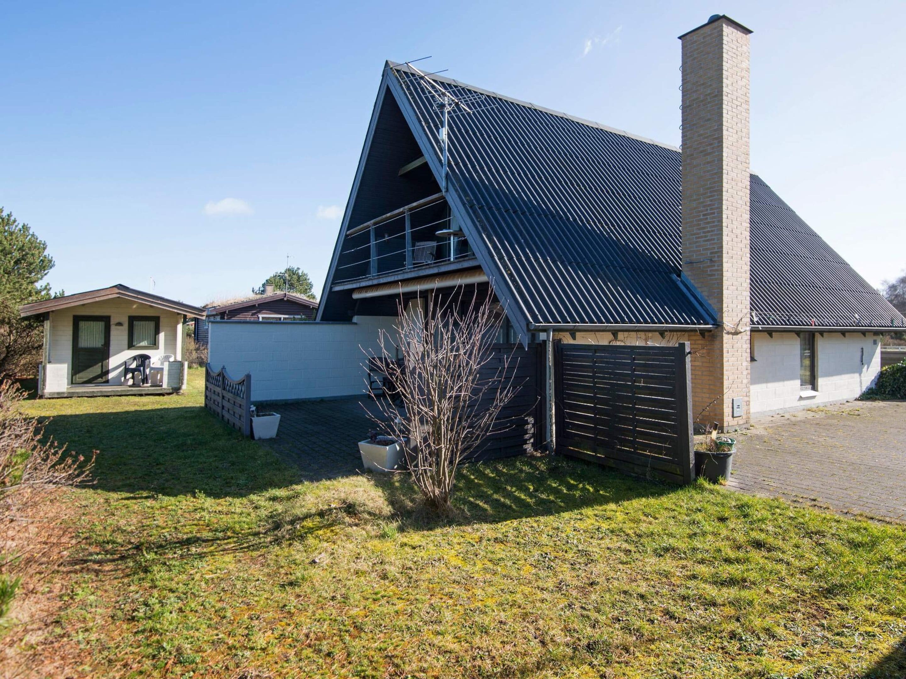 A modern house with a sloped roof, a chimney, and a small garden area.