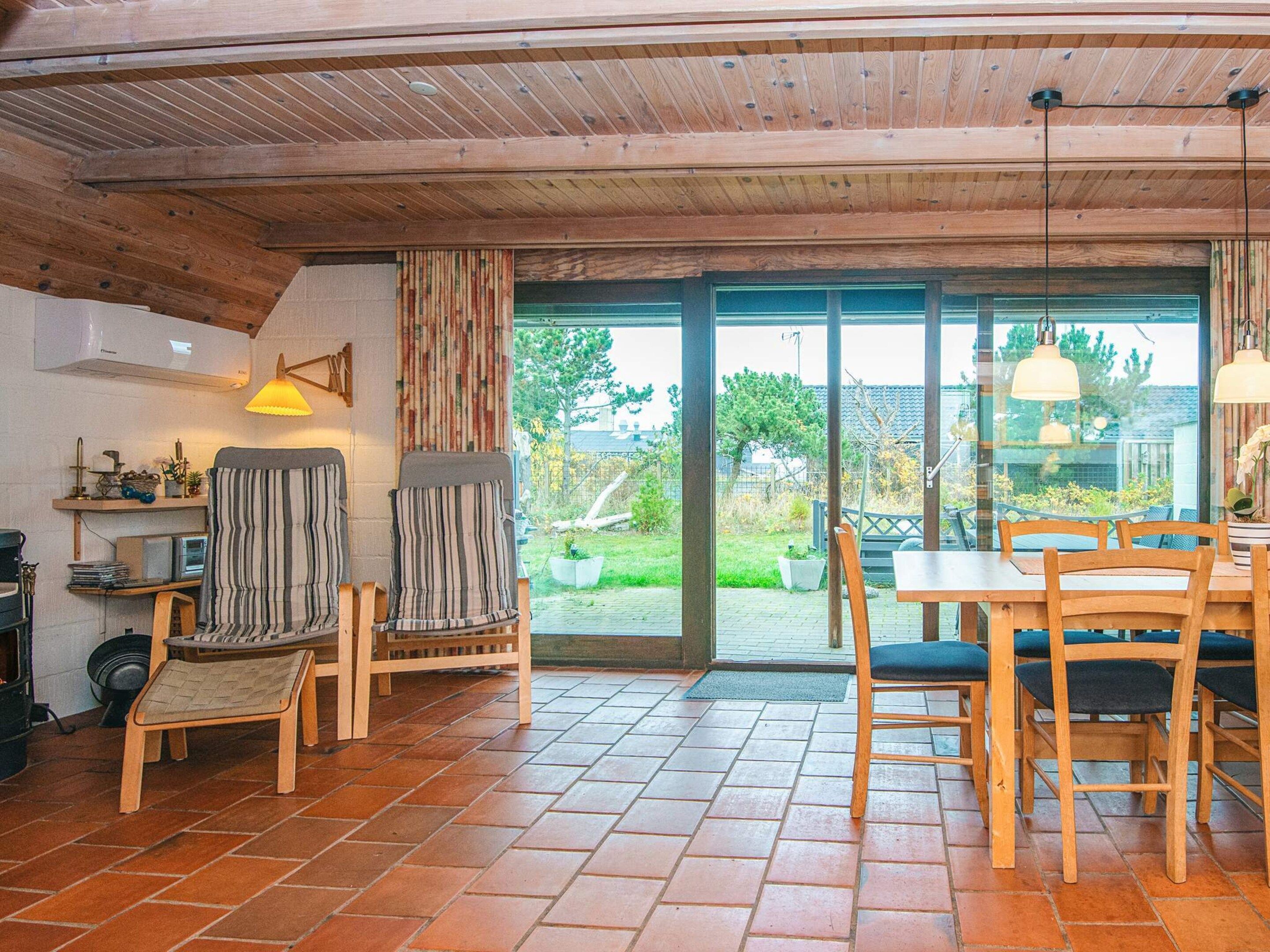 A cozy room with a wooden ceiling, a dining table with chairs, a small stool, and a bench.
