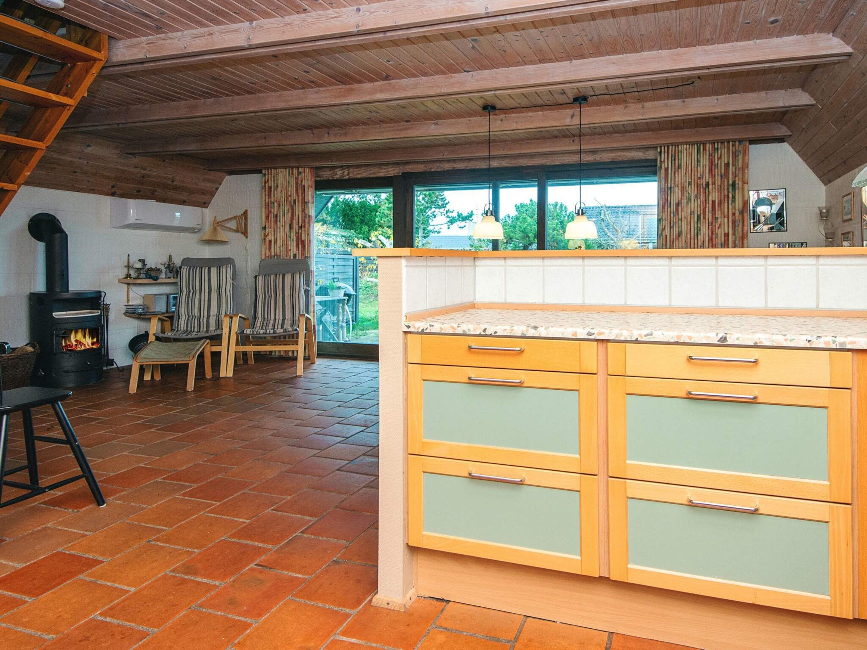 A kitchen with a central island, wooden cabinets, and a fireplace.