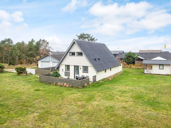 Une maison de plain-pied avec un toit en pente, un porche à l’avant et une petite terrasse.