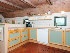 Une cuisine avec des meubles en bois, un lave-vaisselle et une fenêtre donnant sur un beau paysage.