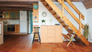 Une cuisine avec des meubles de rangement en bois, un réfrigérateur et un escalier en bois.