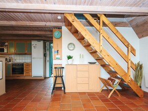 Une cuisine avec des meubles de rangement en bois, un réfrigérateur et un escalier en bois.