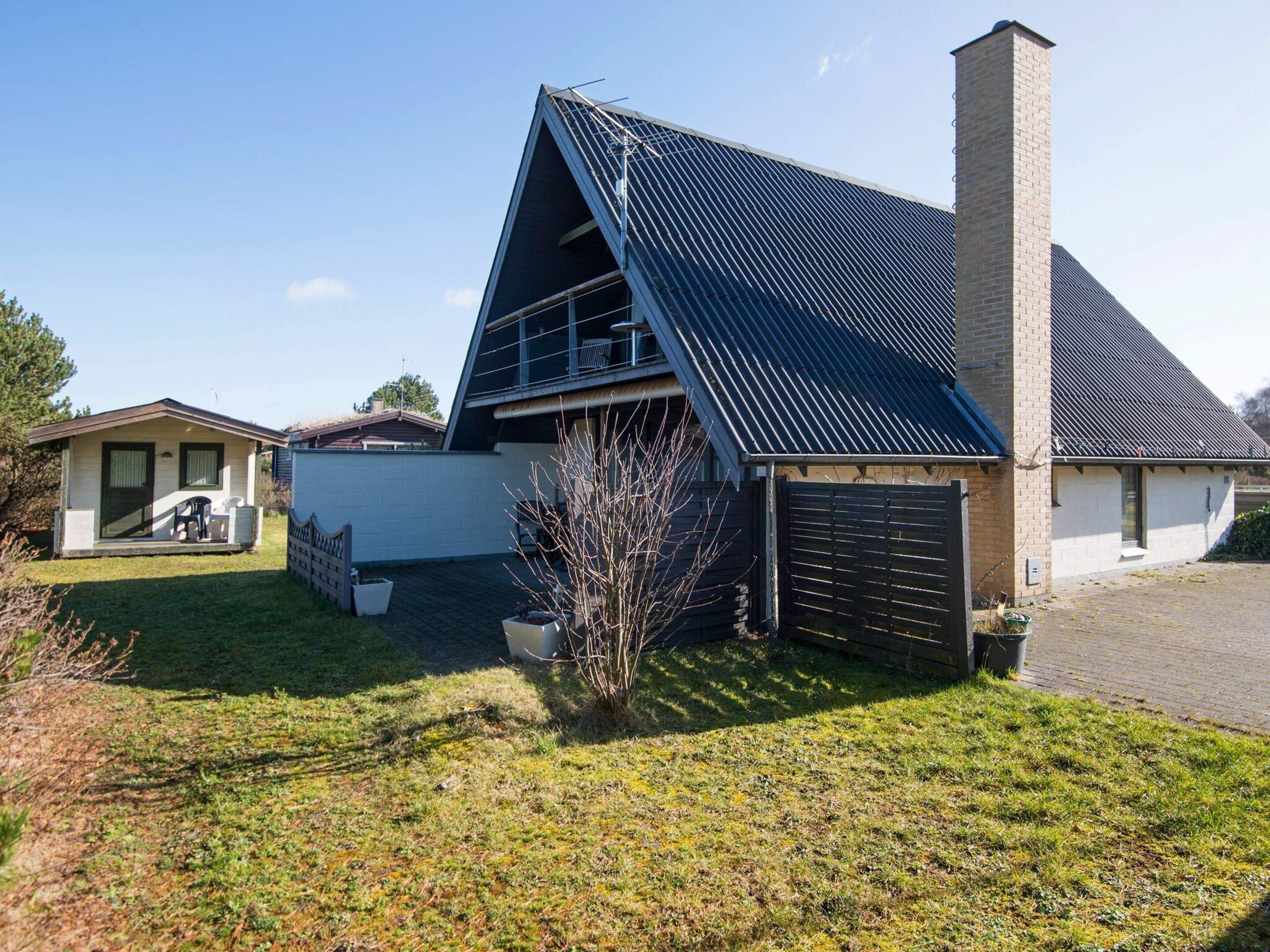 A modern house with a sloped roof, a chimney, and a small garden area.