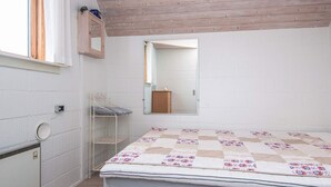 Un dormitorio con una cama, un estante pequeño, un espejo y una ventana.