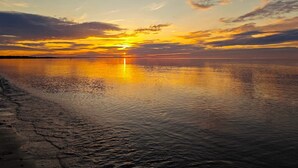 Un cuerpo de agua tranquilo reflejando un atardecer con un horizonte despejado.