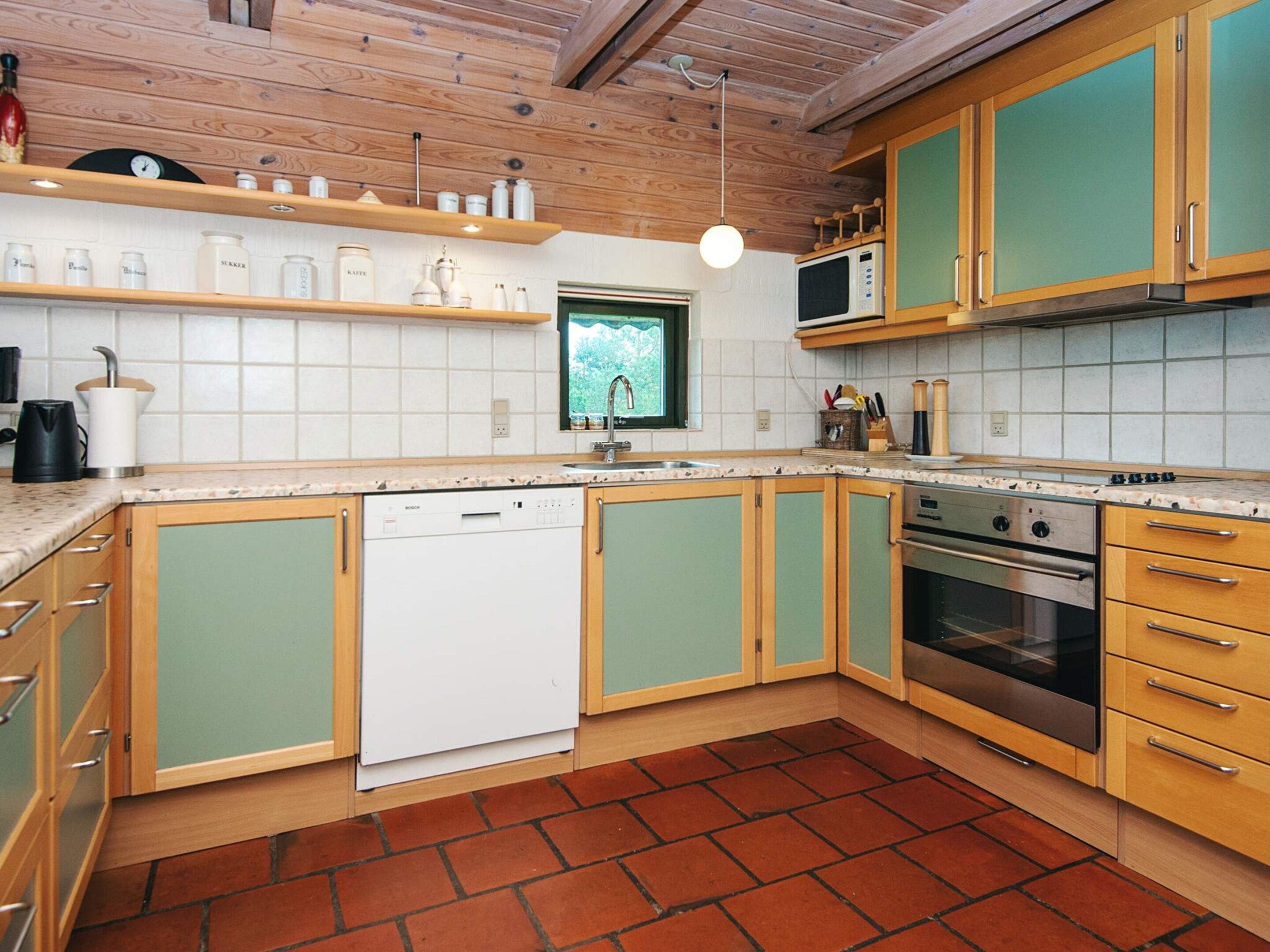 Ett kök med träskåp, diskmaskin, spis och mikrovågsugn.