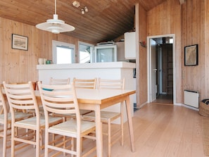 A wooden interior with a dining area, kitchen, and a hallway leading to another room.