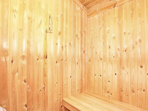 A wooden sauna room with a bench and a wooden wall with a thermometer. - 10 Person Holiday Home in Albaek (Aalbaek)
