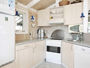 Une cuisine avec des meubles de rangement en bois, un fourneau blanc, un four à micro-ondes et un évier.