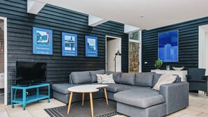 A modern living room with a grey sectional sofa, a small round table, a TV on a stand, and framed artwork on the wall. - 8 Person Holiday Home in Glesborg-by Traum (Glesborg)