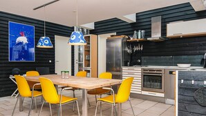 A modern kitchen with a wooden table and yellow chairs, a black and white color scheme, and a large window. - 8 Person Holiday Home in Glesborg-by Traum (Glesborg)