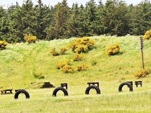 A grassy field with several wooden benches and tire barriers.