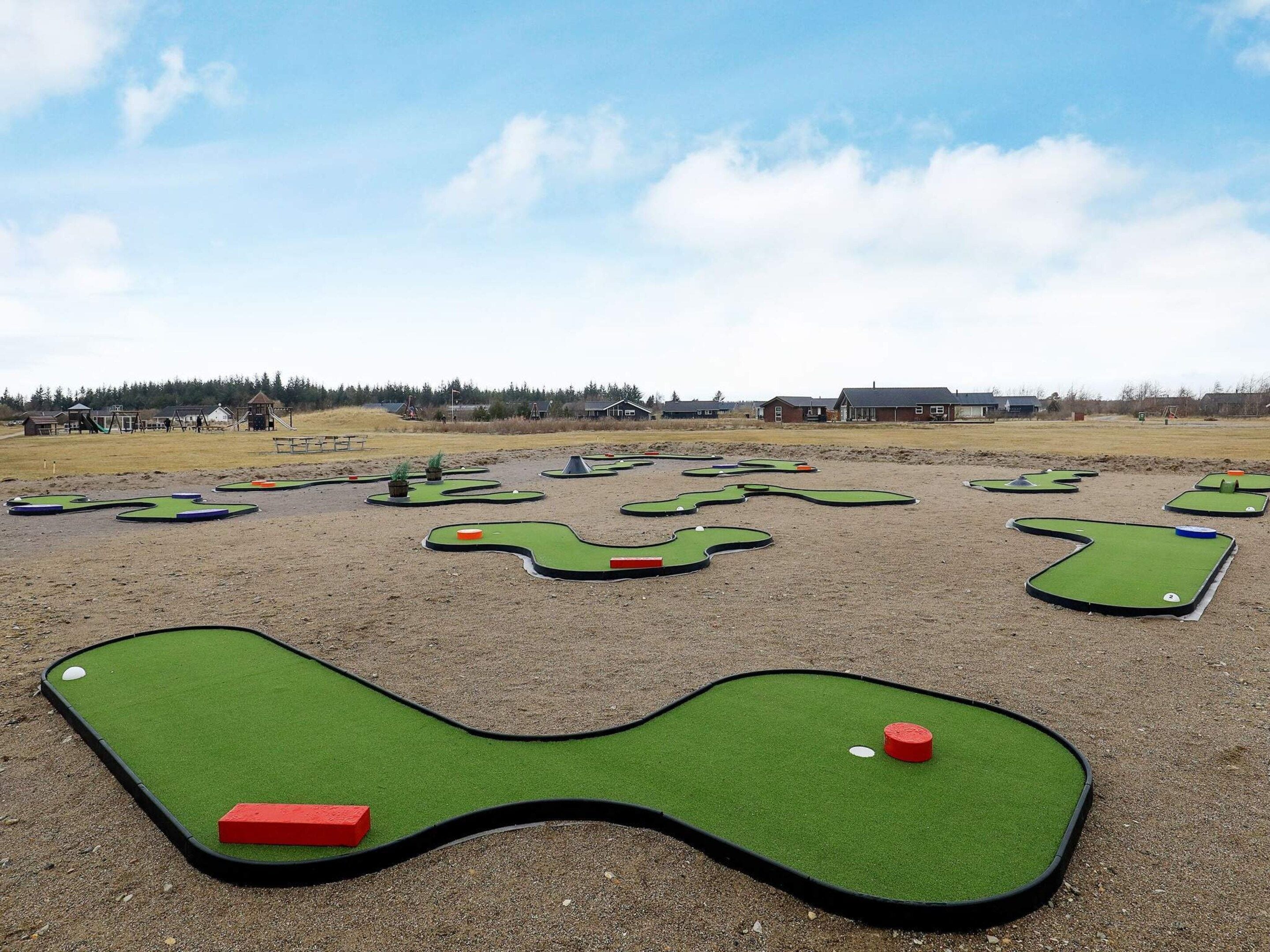 En minigolfbane med flere huller og en klar himmel.