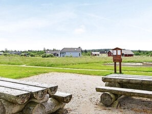 A rural setting with a small wooden structure, possibly a shed or storage, and a clear sky.