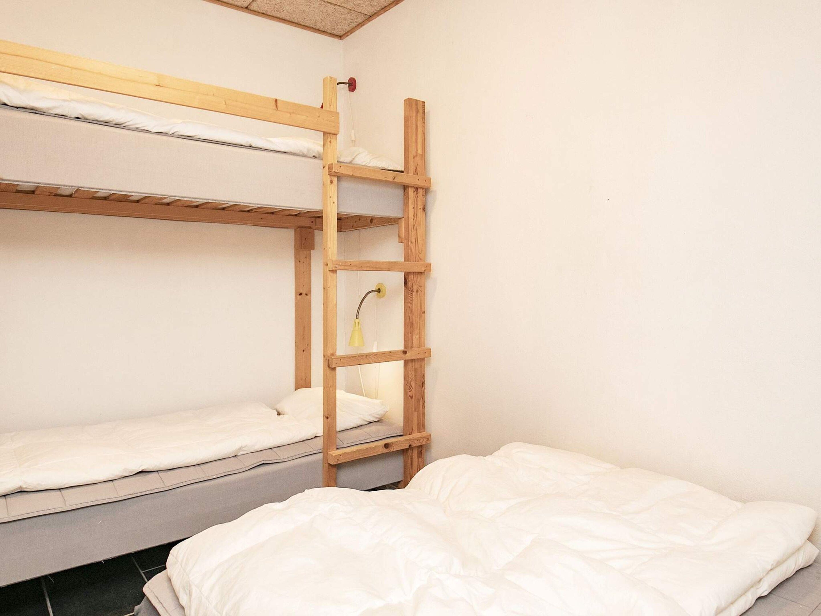 Une chambre avec un lit superposé, une échelle en bois et un lit simple.