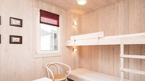 Een houten kamer met stapelbedden, een enkele stoel en een tafel.