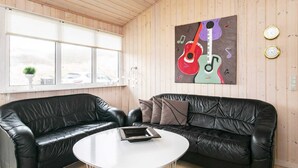Een kamer met twee zwarte leren banken, een witte ronde tafel en een houten plafond.