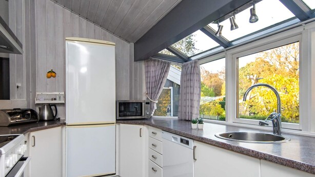 A compact kitchen with white cabinets, a microwave, a kettle, and a sink under a skylight. - Luxury Spa Retreat - By Traum Ferienwohnungen (Glesborg)