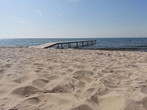 A sandy beach with a wooden pier extending into the water. - 4 Star Holiday Home in Rodby (Rodby)