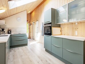 Een moderne keuken met houten lambrisering, een inbouwoven en een groot raam.